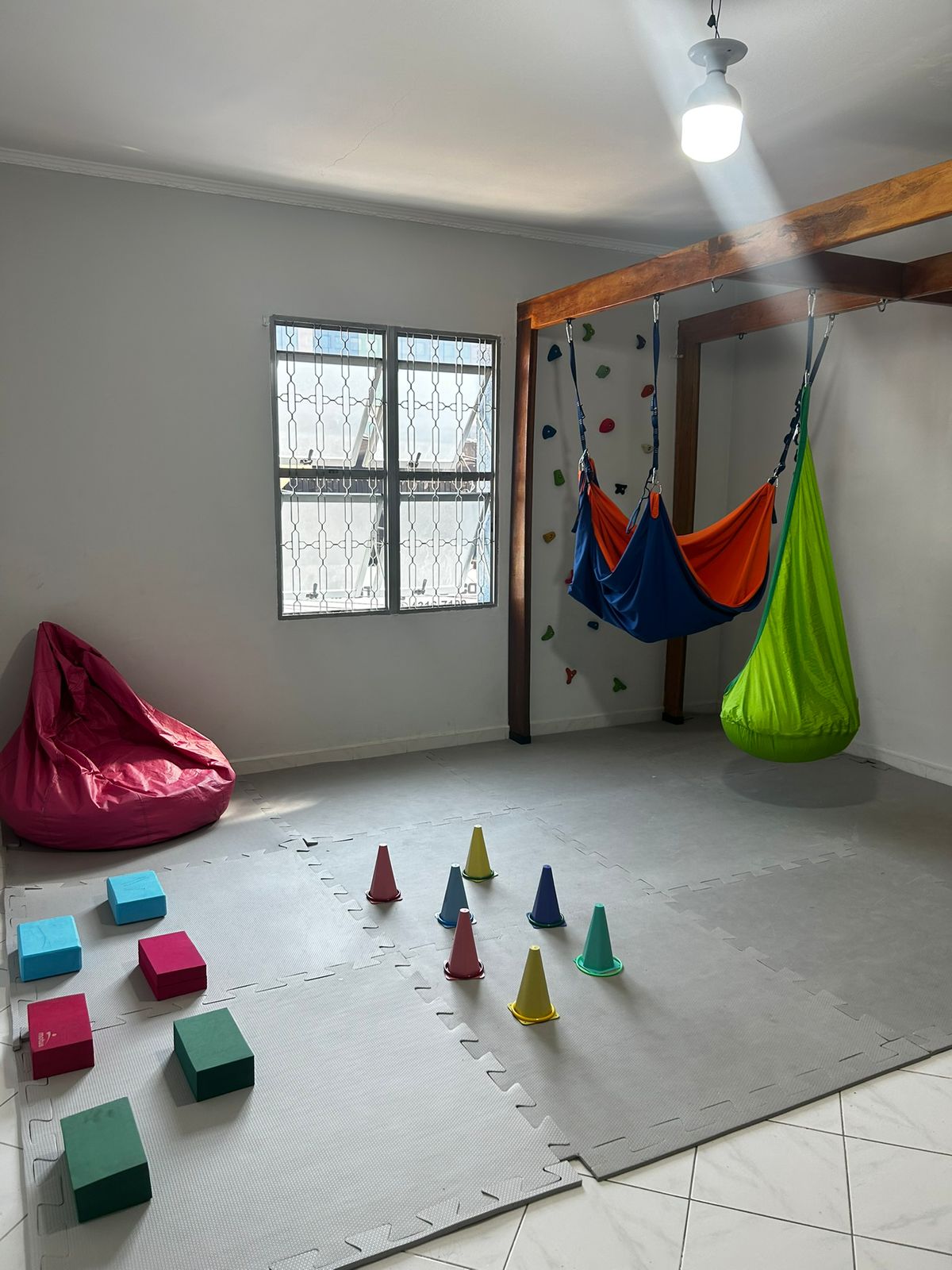 Sala real com balanços terapêuticos, tatame e materiais de integração sensorial